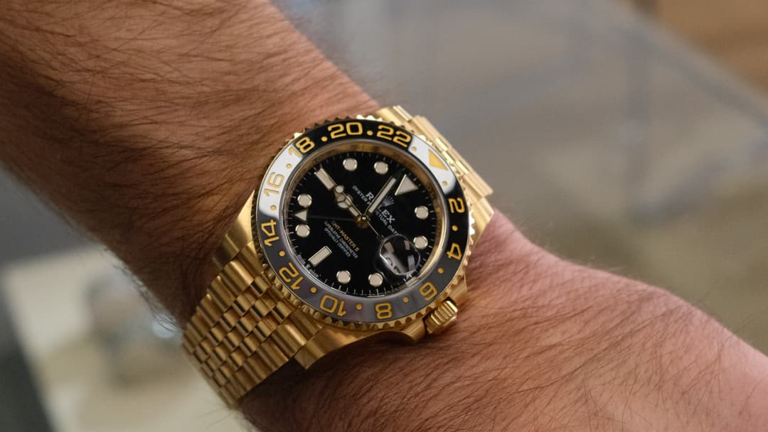 18k yellow gold Rolex GMT-Master II with black ceramic bezel on wrist — luxury watches at Gold & Diamond Company